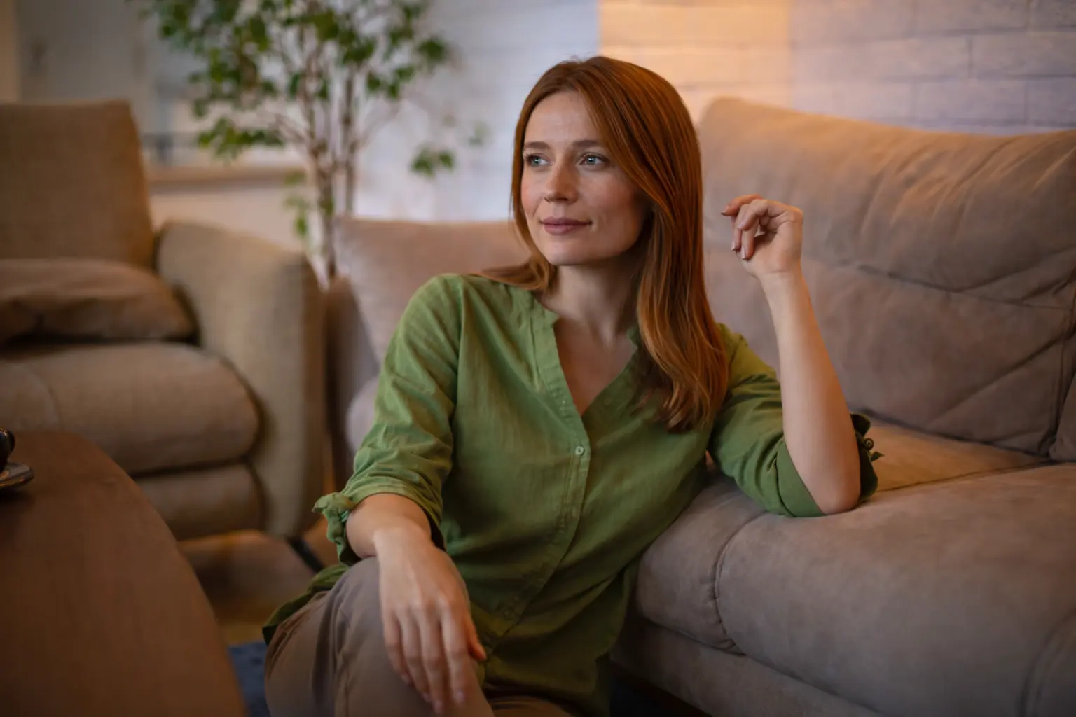 Woman sitting in a modern living room, reflecting on Asset Anchor net worth and financial constraints