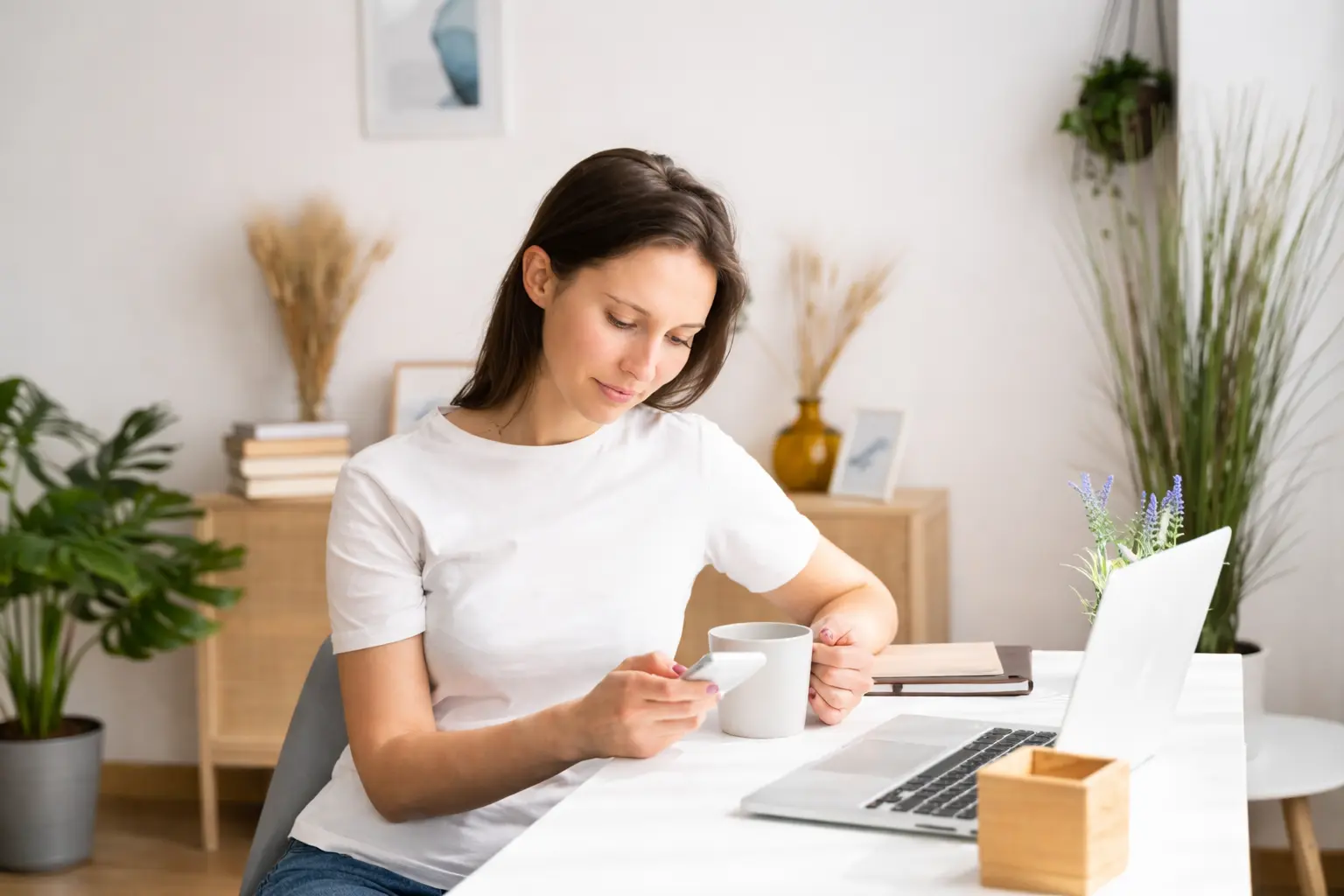 Woman checking phone at desk as banks post deposits at different times during early morning settlement window