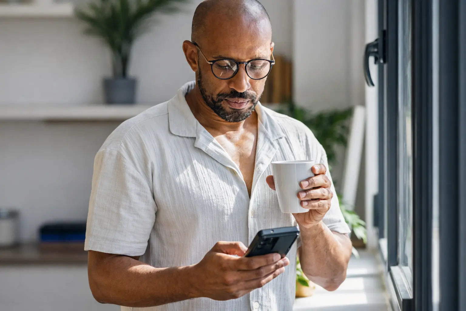 Man checking bank app in morning light illustrating deposit timing delay