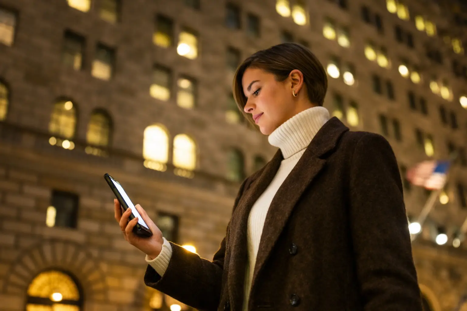American woman checking her phone at night as she waits for a direct deposit at midnight to post in her bank account.