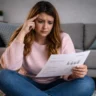 Woman reviewing household bills, reflecting financial control anxiety amid rising living costs
