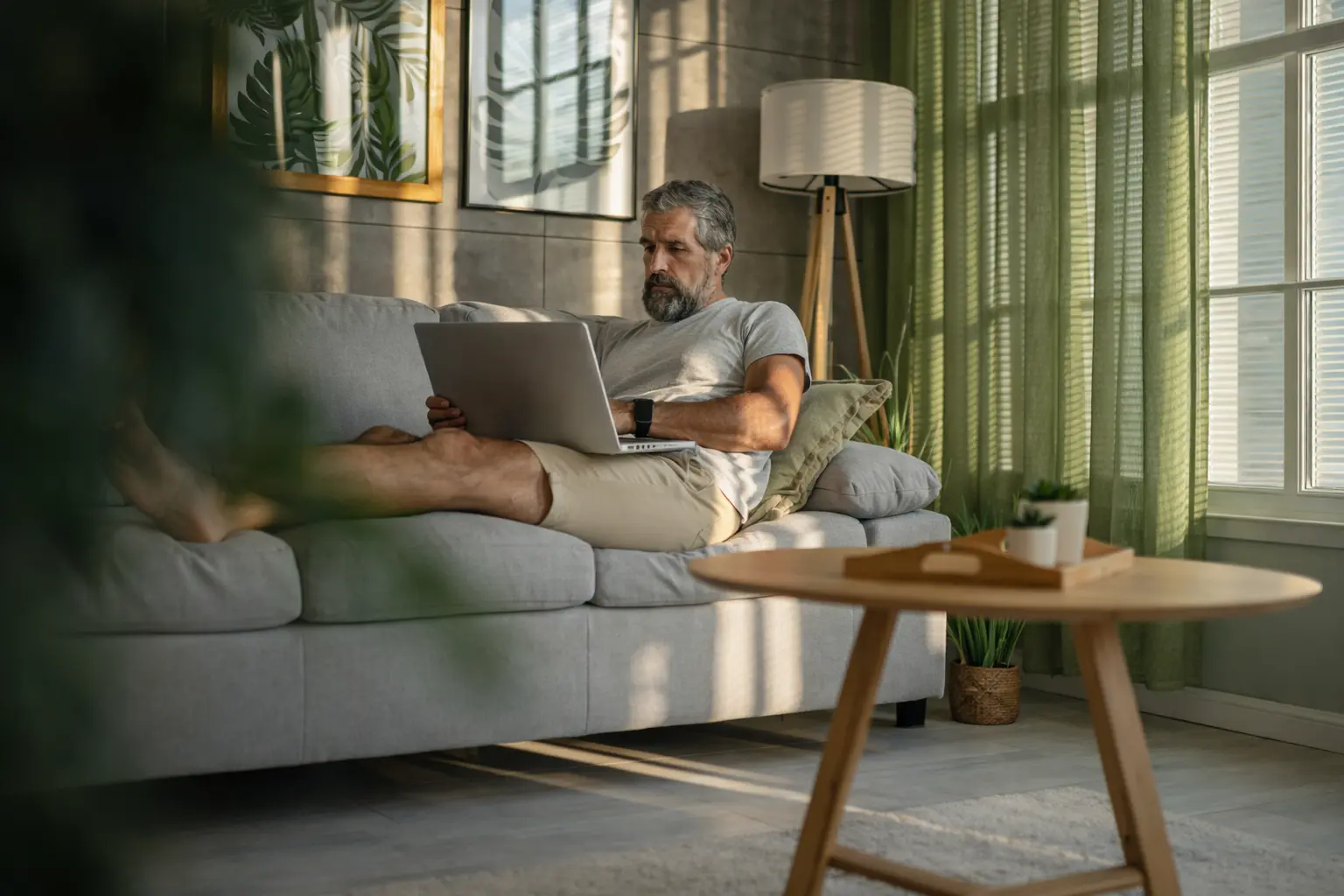 Man reviewing finances on a laptop at home, reflecting financial discipline through careful planning