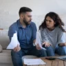 Couple discussing household bills at home, reflecting financial stability anxiety during budget planning