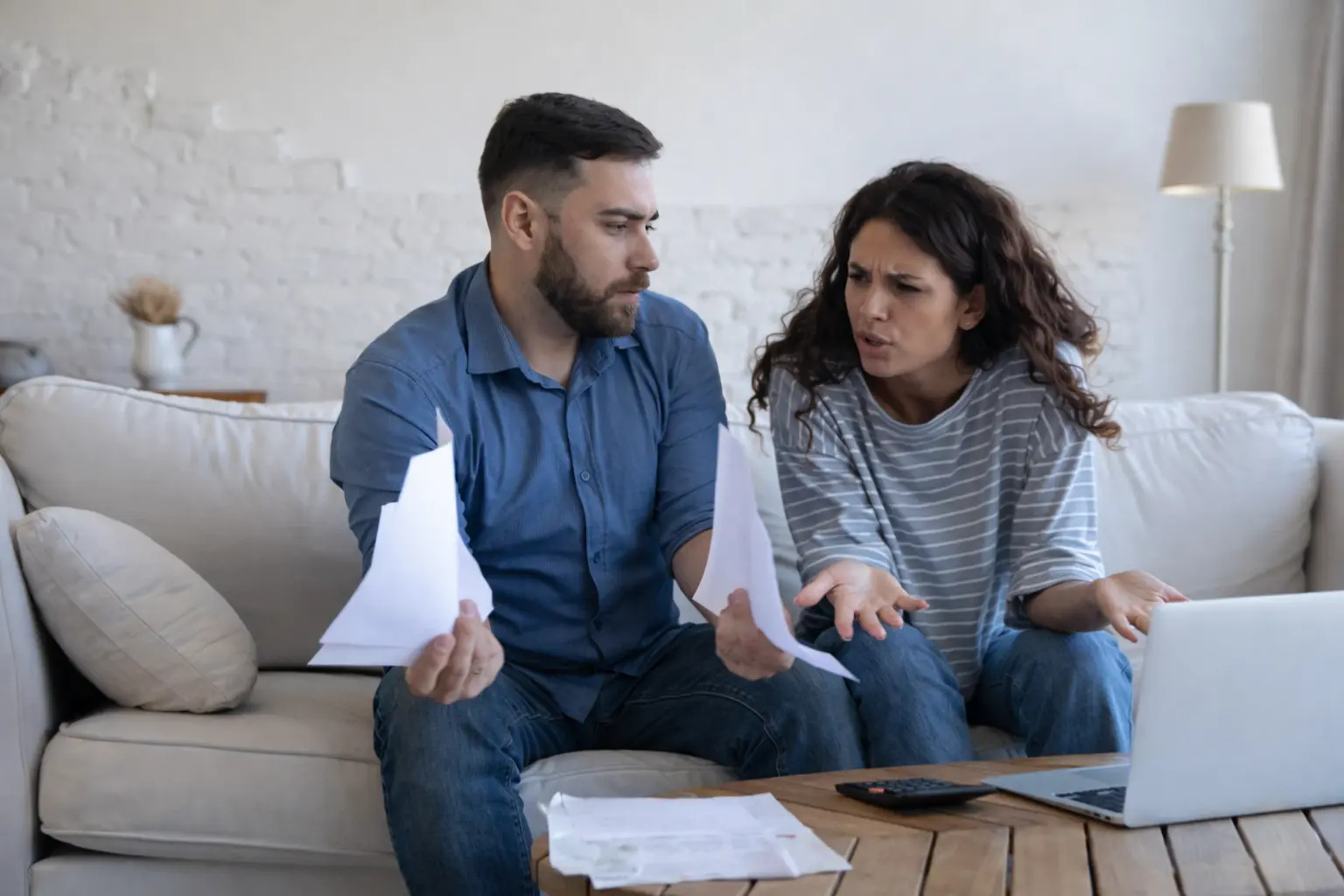 Couple discussing household bills at home, reflecting financial stability anxiety during budget planning