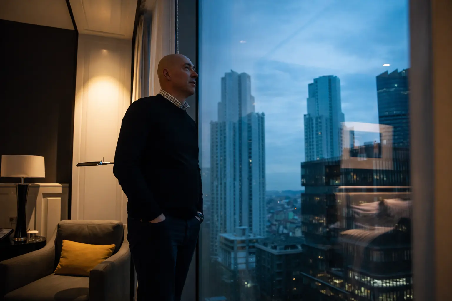 Professional man looking out from a high-rise apartment window, illustrating Golden Cage finance pressure