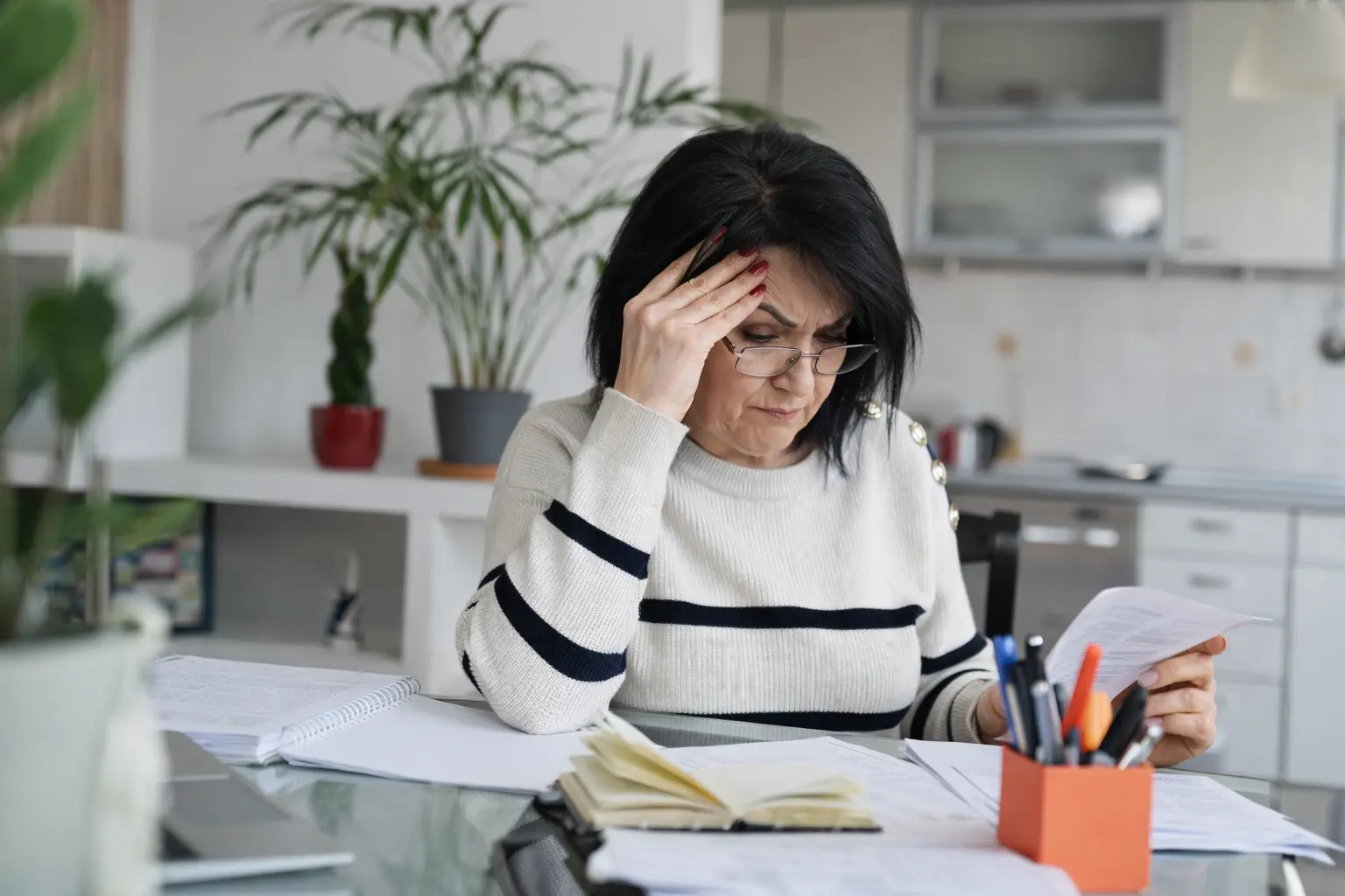 Woman reviewing financial documents at home, practicing good money habits through organized budgeting
