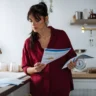 Woman reviewing financial documents at home, illustrating the hidden cost of always maintaining strict money discipline