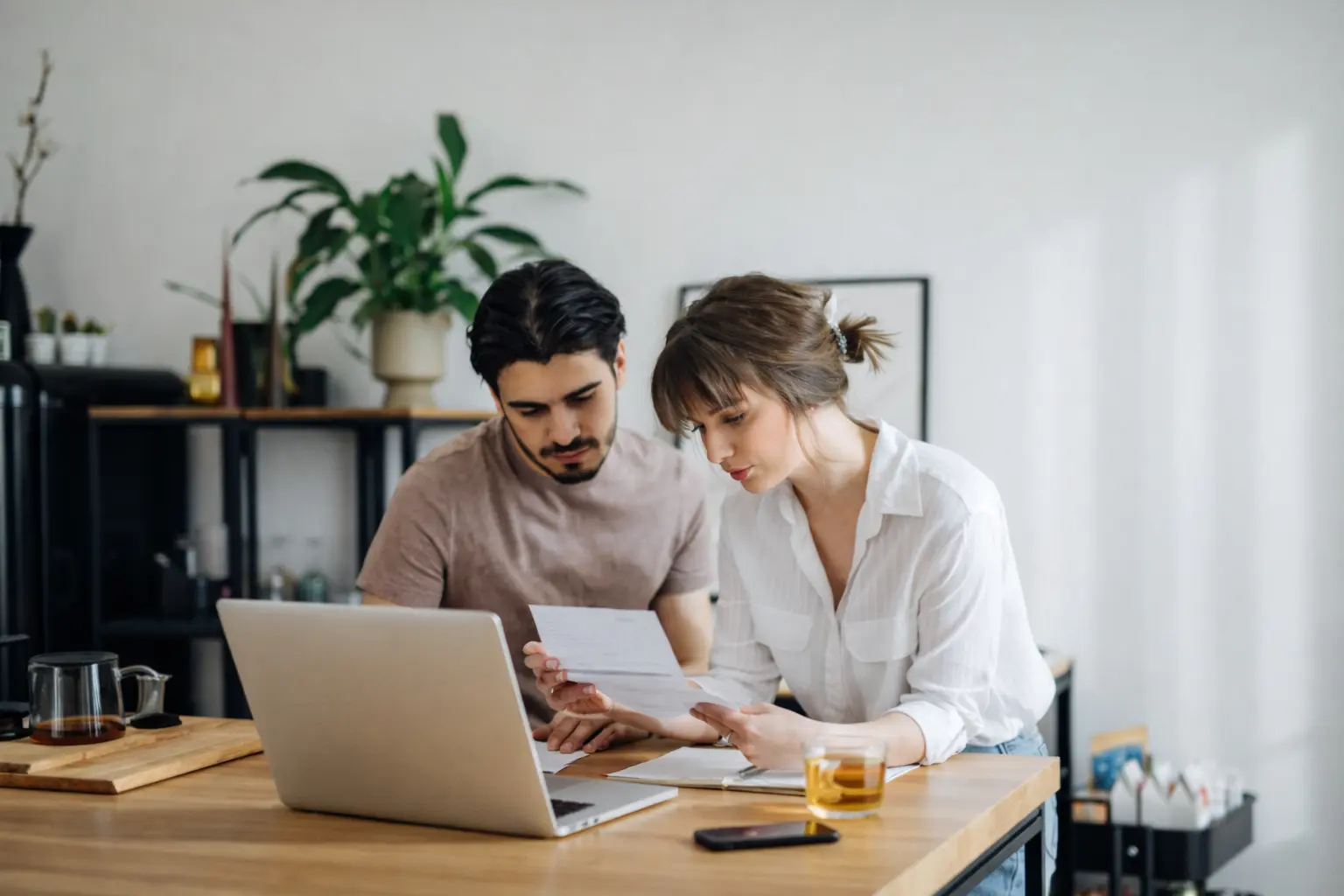 Couple reviewing household bills at home, reflecting money management anxiety while planning monthly expenses