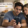 Couple checking phone while federal payment status shows approved sent pending with $0 balance