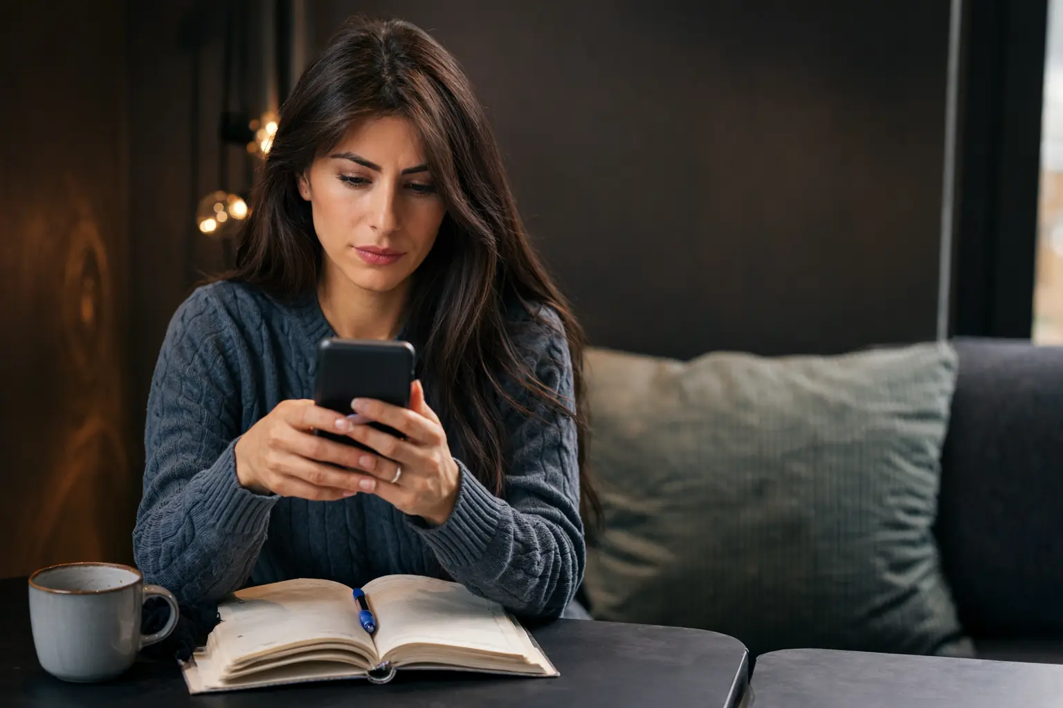 Woman holding a smartphone showing a $0.00 bank account balance and a Monday direct deposit delayed message.