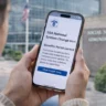 Person checking smartphone showing SSA national system change alert in front of Social Security Administration building