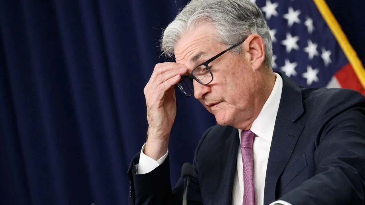 Person at a laptop in a home office reviewing a savings account dashboard with cursor hovering over a transfer button on Jerome Powell decision