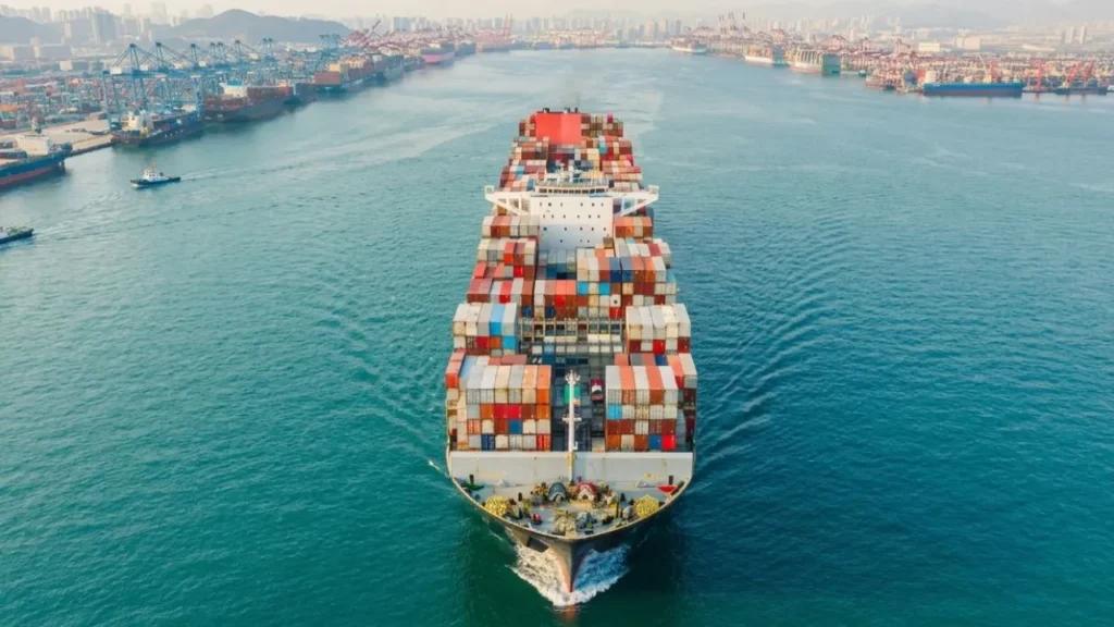 The Inflation Trap That Backed Warsh Into a Corner 3 A massive container ship loaded with cargo containers traveling on open water, illustrating global maritime trade bottlenecks that keep domestic wholesale pricing metrics high while the Federal Reserve interest rate right now stays locked.