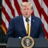 President Donald Trump speaking at a podium with American flags behind him