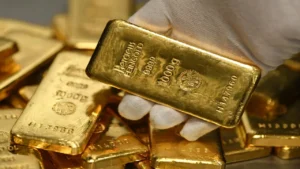 Latest U.S. Financial News and Analysis 7 A gloved hand holds a one-kilogram fine gold bar above a stack of gold bullion bars.