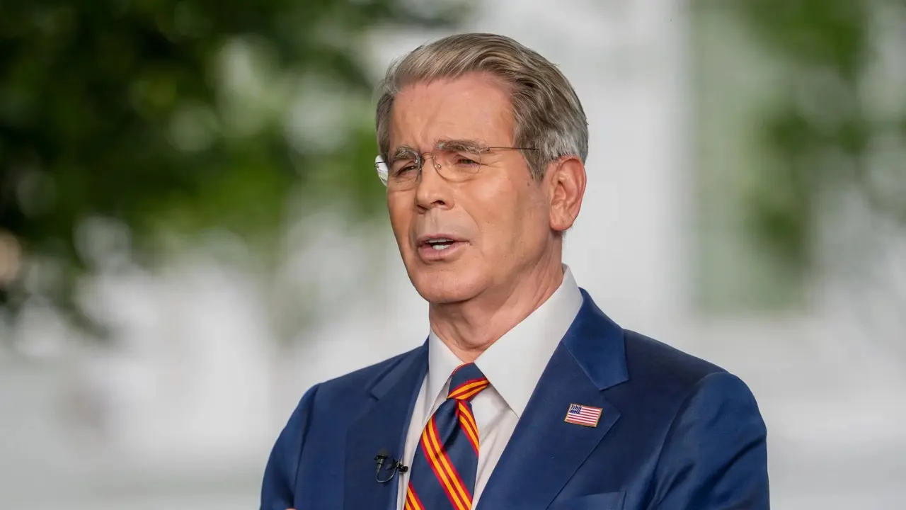U.S. government official speaking outdoors in a navy suit and American flag pin
