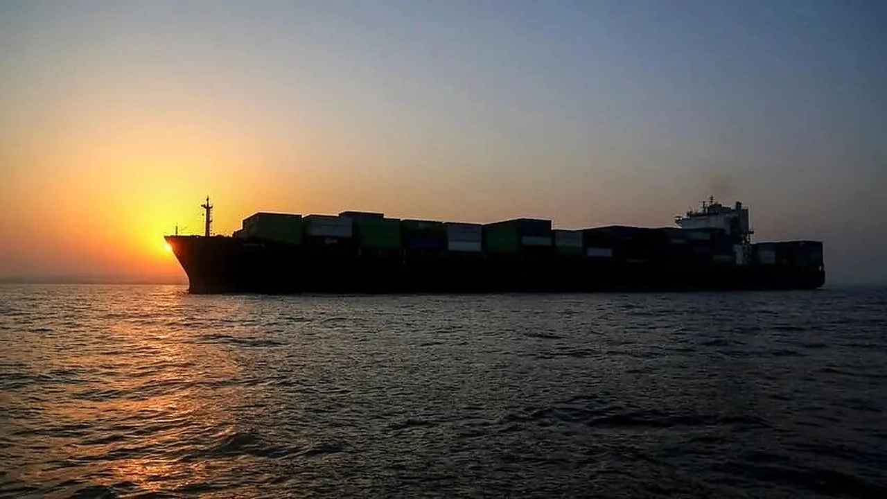 Large cargo ship sailing at sunset as Iran keeps the Strait of Hormuz closed pending U.S. commitments