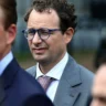 Anthropic executive pictured in a gray suit and blue glasses
