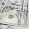 Close-up of overlapping U.S. $100 bills illustrating the Federal Reserve's report on slower consumer credit growth in August 2026.