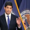 Federal Reserve official speaking at a podium in front of Federal Reserve flags.