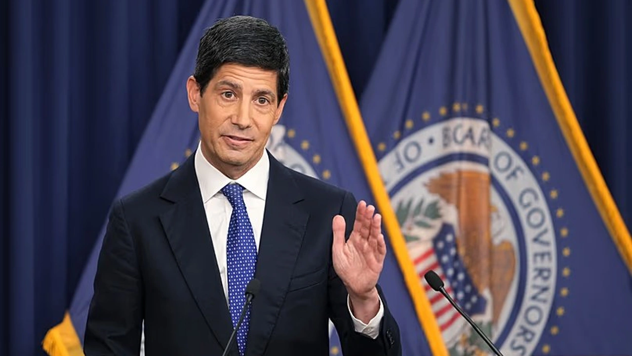 Federal Reserve official speaking at a podium in front of Federal Reserve flags.