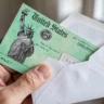 Hand holding a U.S. Treasury check in a white envelope, illustrating automatic IRS adoption tax credit refunds in 2026.