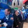 Trader monitoring stock market charts on multiple screens at the New York Stock Exchange.
