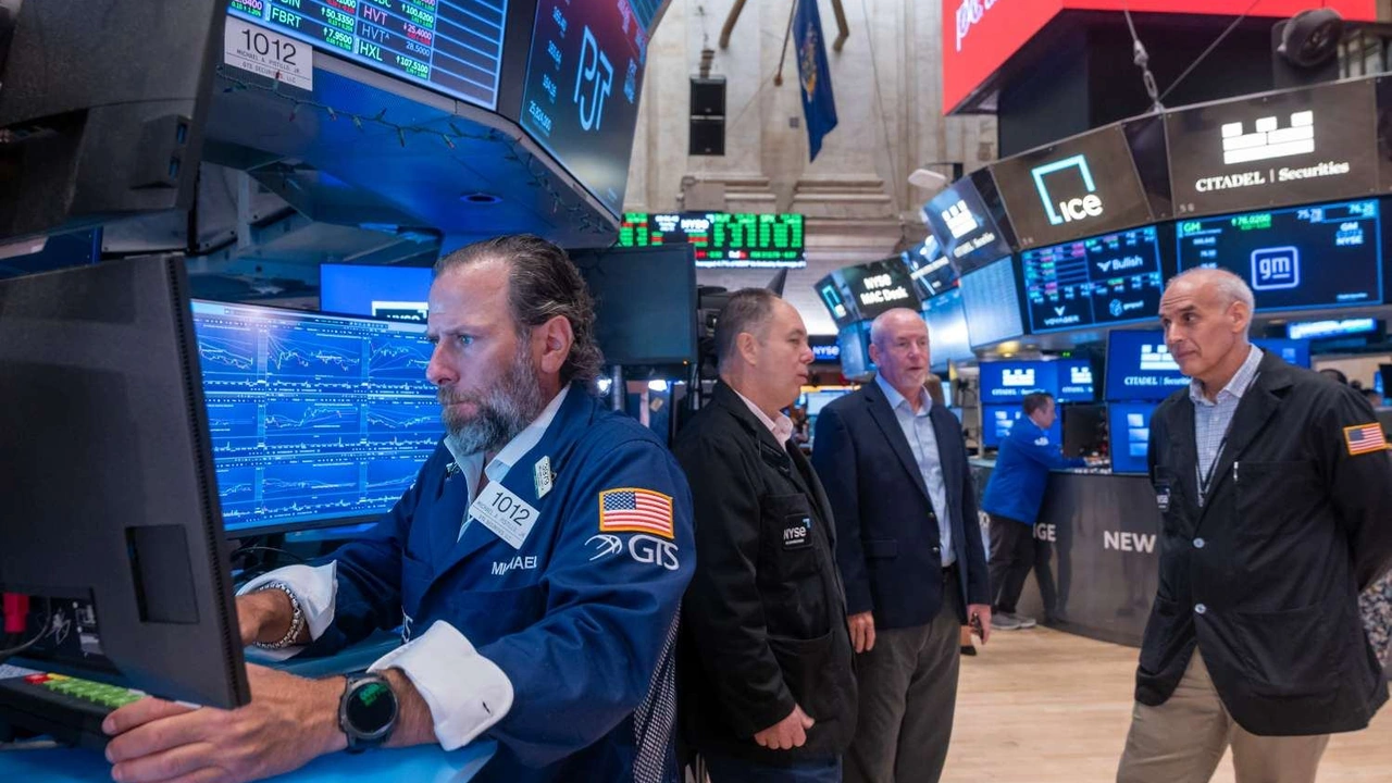 Trader monitoring stock market charts on multiple screens at the New York Stock Exchange.