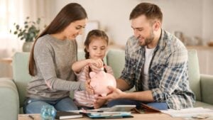 Latest U.S. Financial News and Analysis 19 Parents and their daughter saving money in a piggy bank at home, illustrating family finances and financial security.