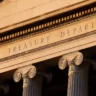 Exterior of the U.S. Treasury Department building in Washington, D.C., showing its engraved name and classical columns.